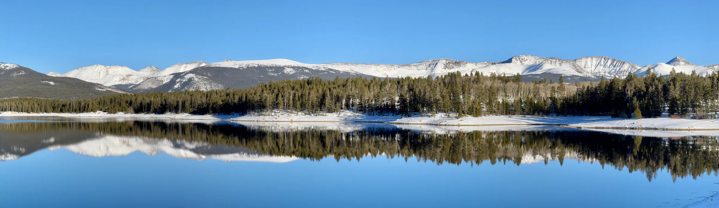 Snow-covered peaks and pine forest reflected in a still lake near Leadville, Colorado